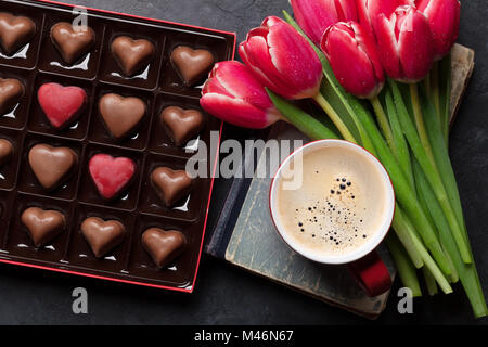 Red tulip bouquet di fiori, la tazza di caffè e cioccolato cuori in confezione regalo. Il giorno di San Valentino biglietto di auguri. Vista superiore Foto Stock