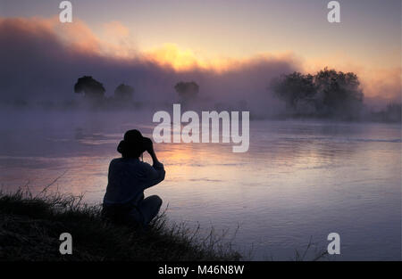 Lo Zimbabwe. Vicino a Victoria Falls. Fiume Zambesi. Sunrise. I turisti. Donna con il binocolo. Foto Stock