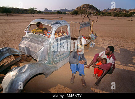 La Namibia. Damaraland. Nei pressi di Twyfelfontein. Damara persone con souvenirshop realizzato dal vecchio carrello. Foto Stock