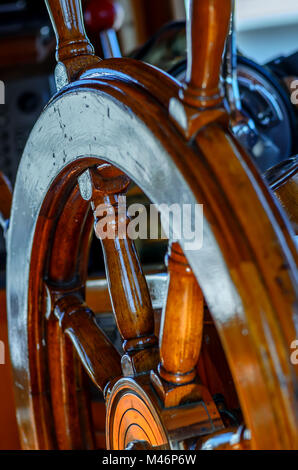 Giallo, vecchio, laccato, volante in legno su un marine yacht close-up, controlli in background Foto Stock