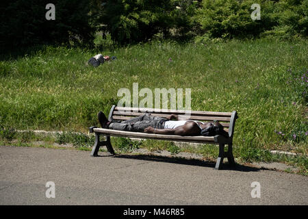 Roma, Italia: Un ragazzo nero dorme su una panchina al sole Foto Stock