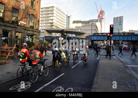 I ciclisti in attesa in corrispondenza di una luce di colore rosso in corrispondenza di un nodo stradale di fronte alla stazione metropolitana di Southwark durante la mattina ora di punta in centro a Londra. pendolari. Foto Stock