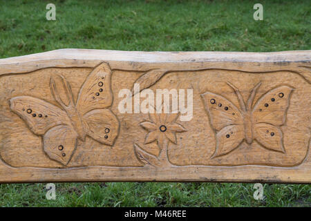 Panca in legno con intricati intarsi a farfalla a Bramshot Agriturismo Country Park vicino a Fleet in Hampshire, Regno Unito Foto Stock