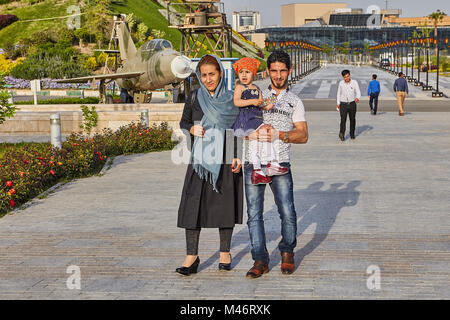 Tehran, Iran - 28 Aprile 2017: donna iraniana in hijab e un uomo con un bambino tra le sue braccia a piedi in Santo Museo di difesa. Foto Stock