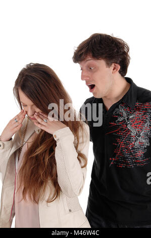 Un giovane uomo in piedi dietro la sua fidanzata e gridava a lei in un grande argomento, isolato per sfondo bianco Foto Stock