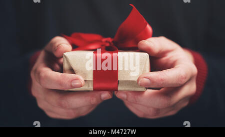 Femmina mani teen mostrano imbarcazioni carta regalo con fiocco rosso Foto Stock