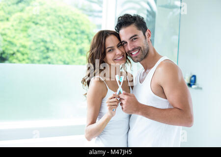 Ritratto di giovane abbracciando tenendo premuto uno spazzolino da denti Foto Stock