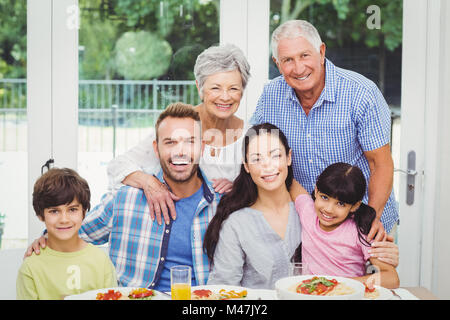 Ritratto di sorridere multi generazione famiglia al tavolo da pranzo Foto Stock
