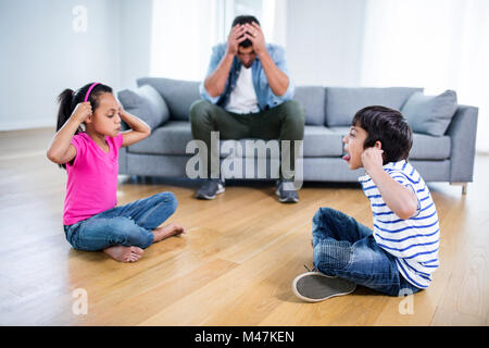 Infastiditi padre seduto sul divano mentre i bambini combattimenti Foto Stock