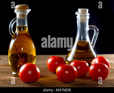 Pomodori e bottiglie di olio d'oliva sul tavolo rustico Foto Stock