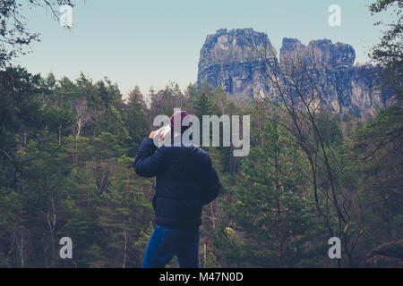 Giovane con telefono cellulare nel paesaggio forestale, Foto Stock