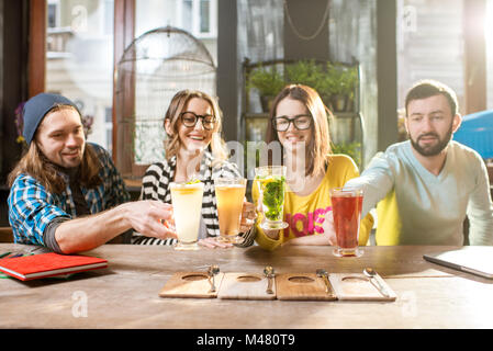 Amici bicchieri tintinnanti nel moderno cafe Foto Stock