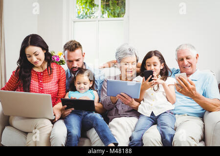 La famiglia utilizzando tecnologie mentre è seduto in divano Foto Stock