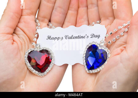 Rosso e blu cuore di gioielli con carta di san valentino sulle mani Foto Stock