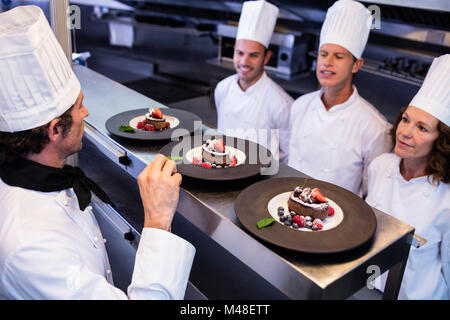 Capo chef ispezione piatti da dessert su alla stazione di ordine Foto Stock