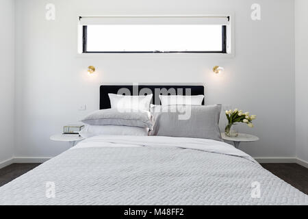 Il lusso moderno e la camera da letto padronale con oro luci da parete e trapunta grigio Foto Stock