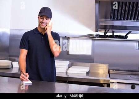 Pizza consegna uomo prendendo un ordine per telefono Foto Stock