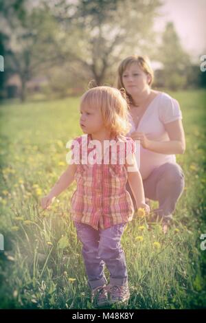 Carino bambina con la sua madre in stato di gravidanza Foto Stock