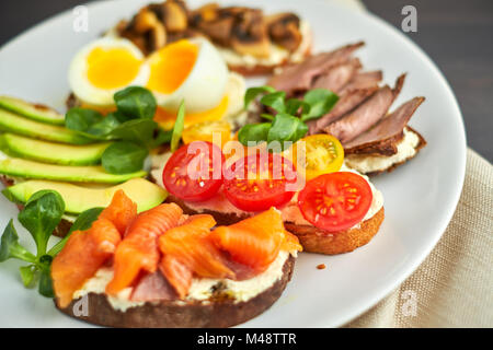 La bruschetta, assortiti, diversi ripieni, su piastre con un soft-uovo sodo in medio Foto Stock