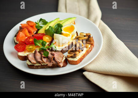 La bruschetta, assortiti, diversi ripieni, su piastre con un soft-uovo sodo in medio Foto Stock