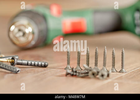 Viti e dispositivi di fissaggio giacciono sullo sfondo del cacciavite Foto Stock