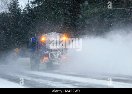 SALO, Finlandia - 9 febbraio 2018: carrello equipaggiato con spazzaneve e sale su strada spandiconcime cancella un'autostrada nel sud della Finlandia durante la bufera di neve, in vista posteriore Foto Stock