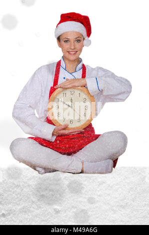 Donna cucinare in Santa hat, yoga orologio sotto neve Foto Stock