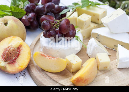 Diversi e deliziosi formaggi e frutta in legno bordo rotondo Foto Stock
