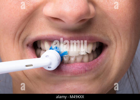 Close-up di una donna di denti con spazzolino da denti elettrico Foto Stock