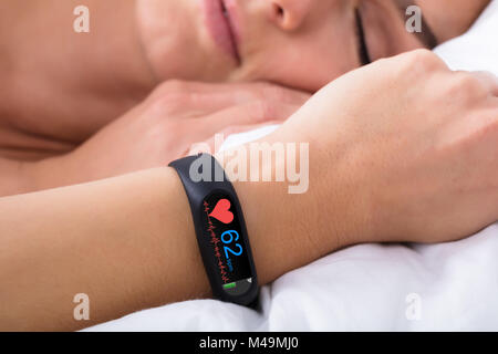 Close-up di attività Fitness Tracker con il battito cardiaco sulla donna di mano sul letto Foto Stock