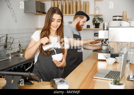 Caffè il concetto di Business - close-up lady barista in preparazione della catenaria e versando il latte nella tazza calda mentre in piedi presso il cafe. Foto Stock