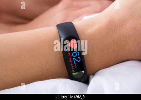 Close-up di attività Fitness Tracker con il battito cardiaco sulla donna di mano sul letto Foto Stock