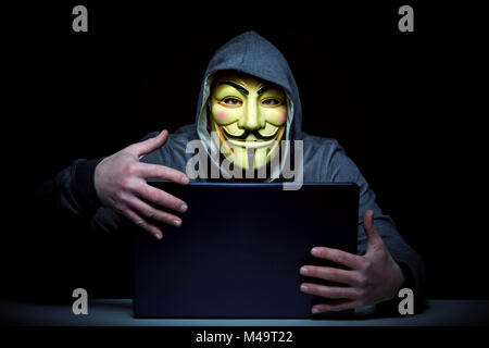 Milano,Italia, Febbraio 2018: Hacker indossare maschera anonimi con i notebook nel buio .foto editoriale. Foto Stock