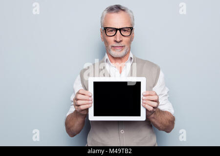 Ritratto di grave calma concentrata virili esperto specialista qualificato uomo beige gilet di maglia camicia bianca tenendo in mano touchpa tablet Foto Stock