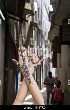 Donna di henna decorate mani giunte in posizione verticale in un vicolo in Stone Town, Zanzibar, Tanzania in una luminosa e soleggiata giornata Foto Stock