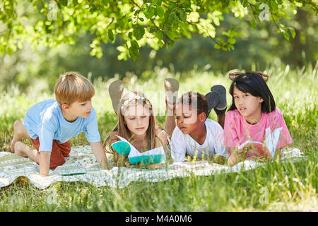Scuola elementare gruppo multiculturale dei bambini imparare insieme nel parco Foto Stock