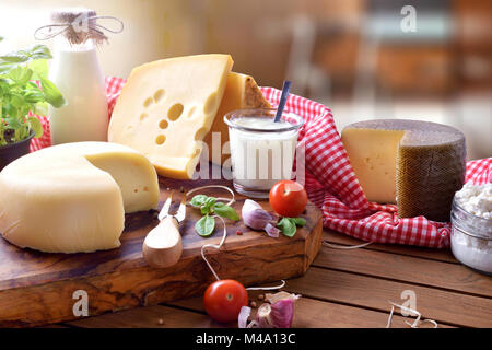 Assortimento di caseificio artigianale prodotti su di un tavolo di legno in cucina rustica. Vista in elevazione. Composizione orizzontale Foto Stock