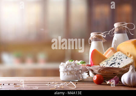 Assortimento di caseificio artigianale prodotti su di un tavolo di legno in cucina rustica. Vista frontale. Composizione orizzontale Foto Stock