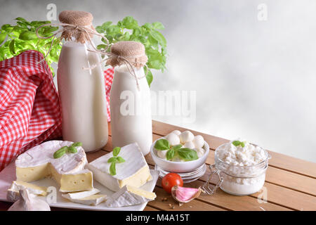 Grande assortimento di caseificio artigianale prodotti su di un tavolo di legno con uno sfondo grigio. Vista frontale. Composizione orizzontale Foto Stock