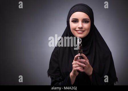 Donna musulmana in abito nero contro uno sfondo scuro Foto Stock