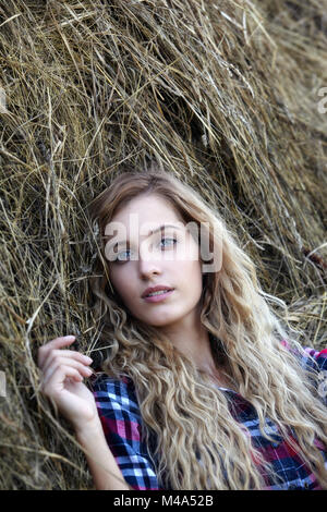 Giovane biondo con gli occhi azzurri country girl vicino haystacks Foto Stock