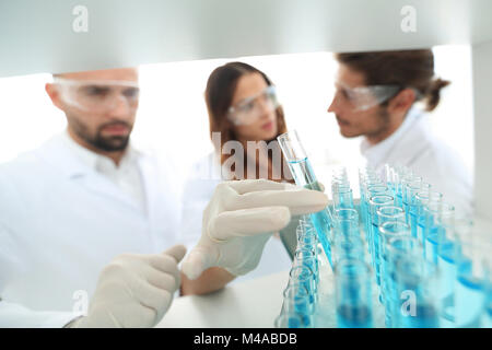 Immagine di sfondo è un gruppo di scienziati che studiano il liquido nel tubo di vetro. Foto Stock