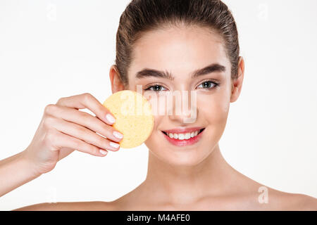 Immagine di attraente dai capelli scuri con donna morbida pelle sana, applicare il make up con spugna cosmetici isolate su sfondo bianco Foto Stock