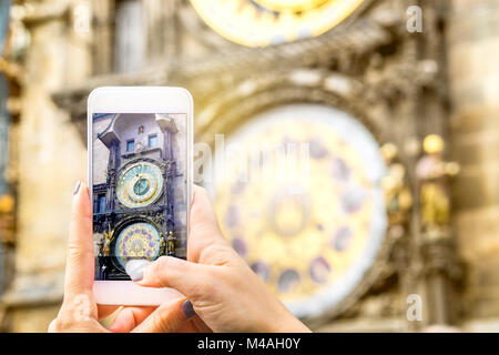 Turistica prendendo foto di una famosa attrazione con lo smartphone. Donna prendendo foto dell'orologio astronomico di Praga nella Repubblica Ceca con mobile camer Foto Stock