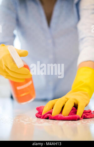 Close up della donna utilizzando spray polacco di pulire la superficie da cucina Foto Stock