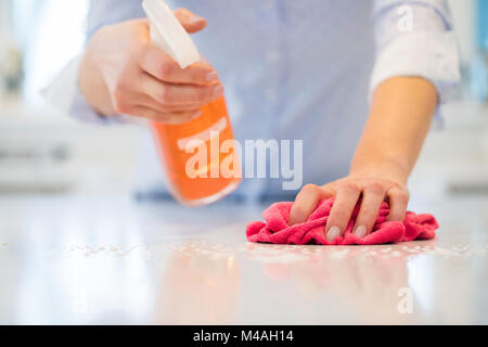 Close up della donna utilizzando spray polacco di pulire la superficie da cucina Foto Stock