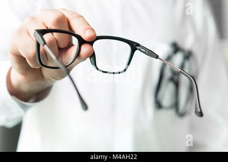 Ottico dando nuovi occhiali per il cliente per il test e il tentativo. Occhio medico mostrando le lenti del paziente. Professional all'ottico optometrista in camice bianco. Foto Stock