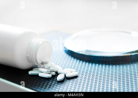 Pillole di perdita di peso su una scala. La dieta medicina versato fuori dal flacone. Foto Stock