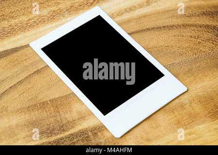 Instant photo frame su un tavolo di legno. Svuotare lo spazio vuoto per l'immagine. Foto Stock