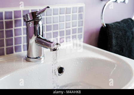 Acqua che scorre da un bagno rubinetto, in un lavandino. Foto Stock